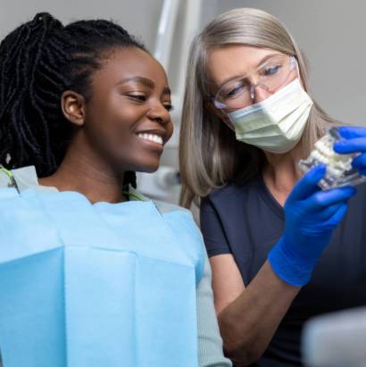 Female,Dentist,Showing,Dentures,To,Her,Patient